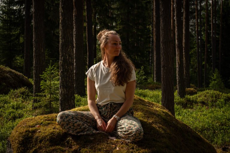 Marielle, eigenaar van Friluft Sweden en host van InnerTrail Sweden zit op een steen in het bos van Zweden