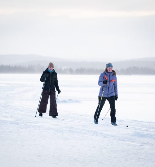 Participants cross-country skiing over a frozen lake at Friluft Sweden during an InnerTrail Sweden retreat, surrounded by snowy landscapes