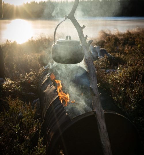 A kettle heating over a campfire in the outdoors during an InnerTrail Sweden retreat at Friluft Sweden